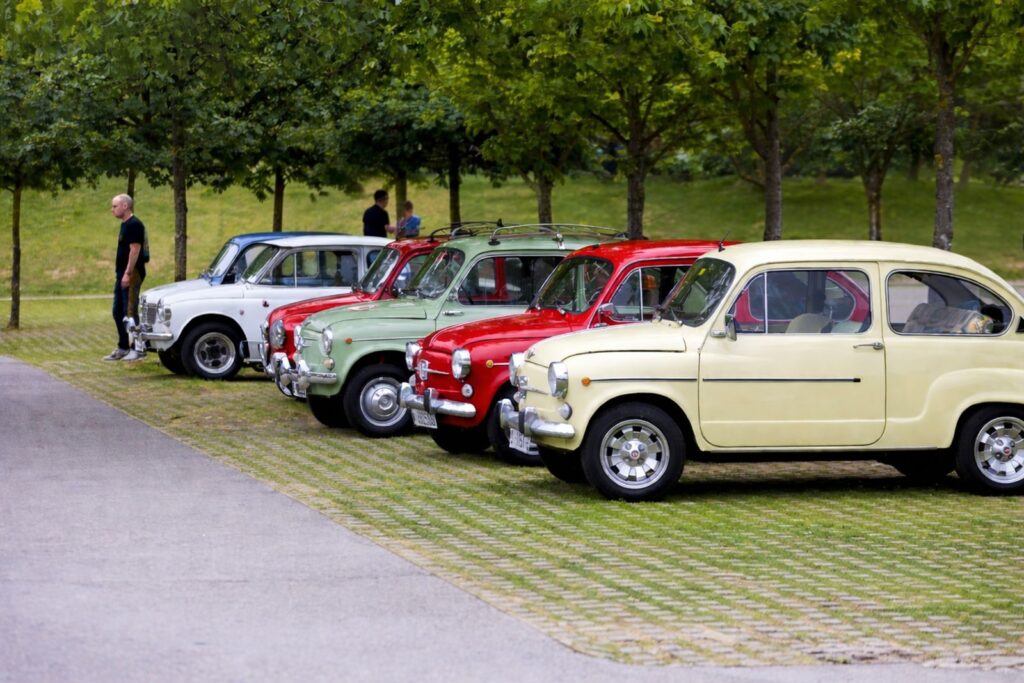 Classic vintage cars on display in a lush outdoor park in Santander, Spain.