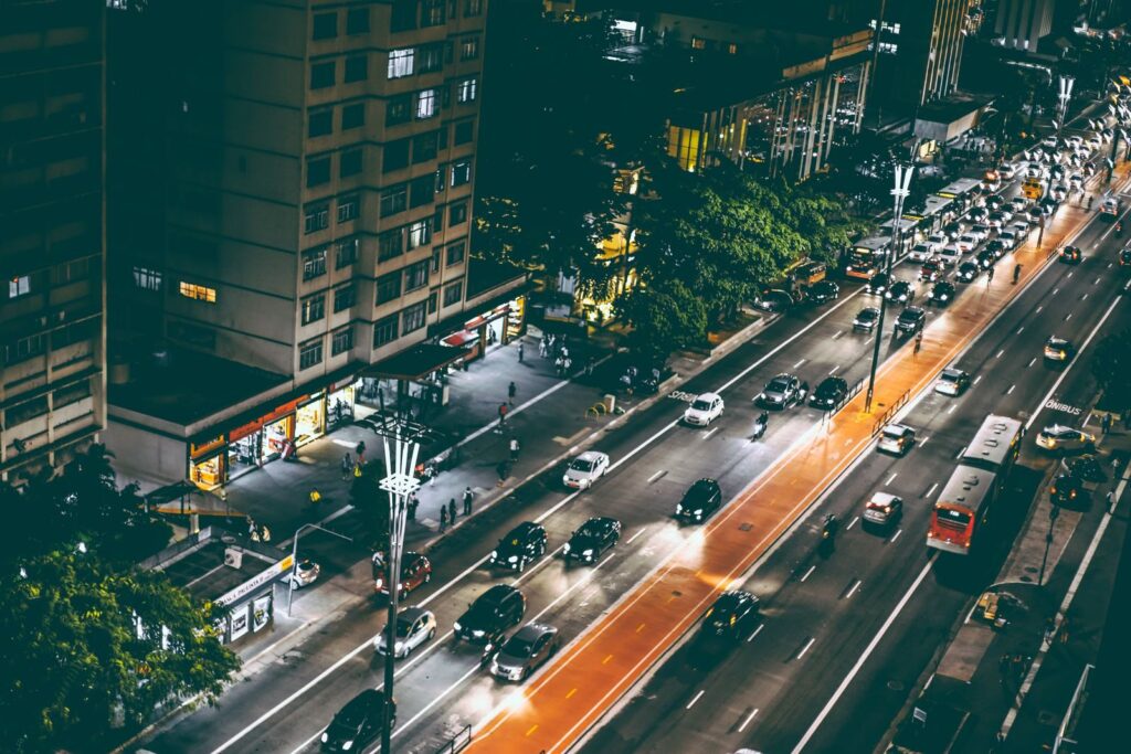 A lively city street at night showcasing vibrant traffic motion and illuminated buildings.