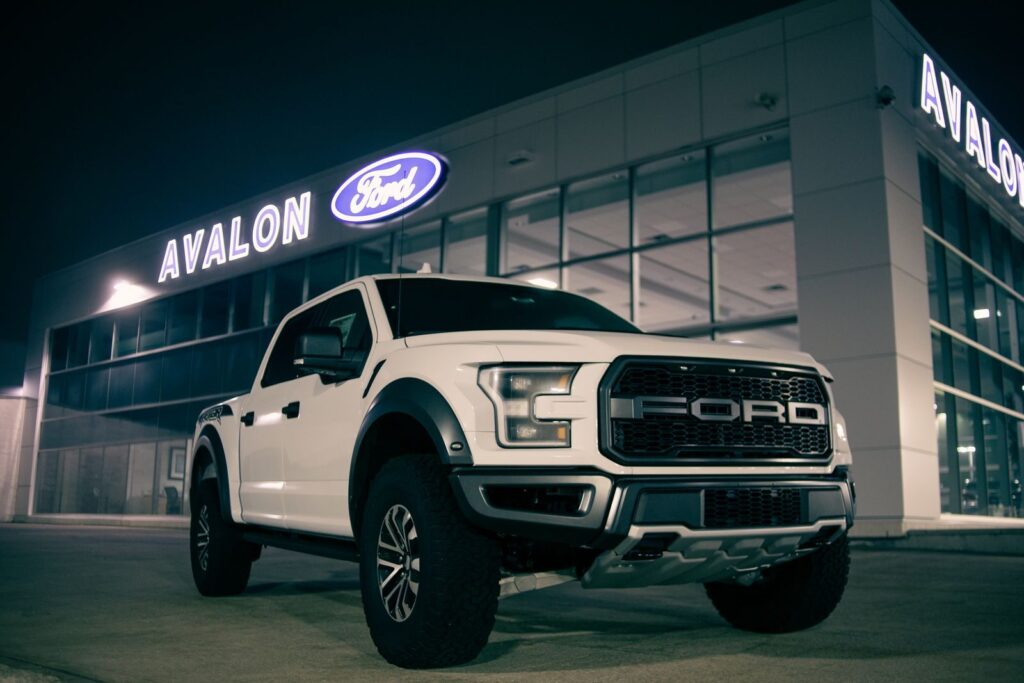 Low angle of modern pickup car with label on bumper on parking lot near retailing salon