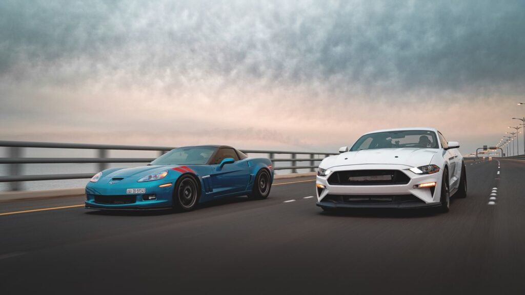 Dynamic capture of two sports cars racing on a highway under a dramatic sky, emphasizing speed and motion.