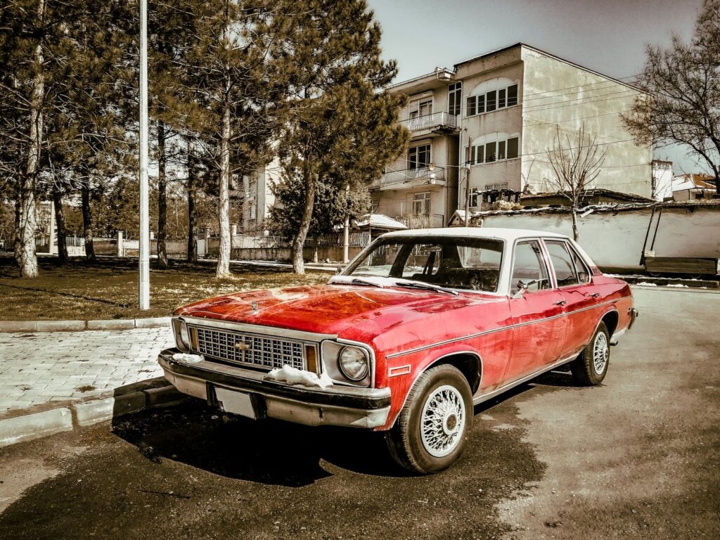 A classic red Chevrolet car parked on a street lined with trees and buildings in Türkiye.