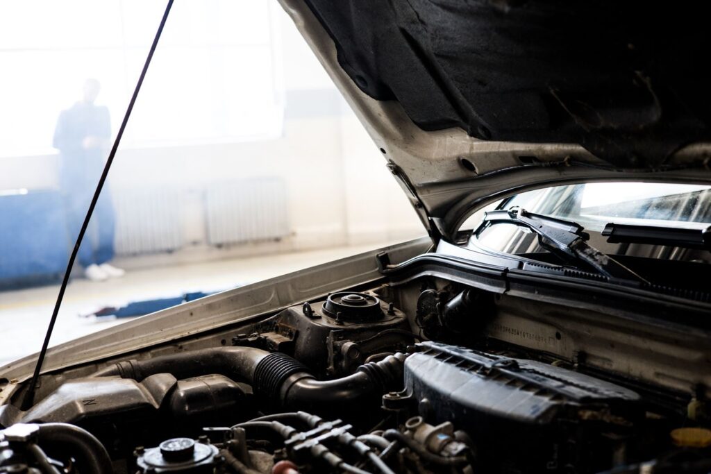Detailed image of a car engine underneath the open hood in a well-lit indoor garage.
