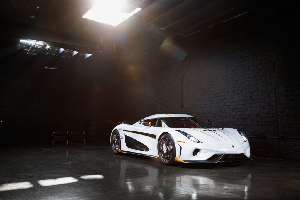 A stunning white Koenigsegg Regera sports car parked in a dimly lit garage, exhibiting luxury and elegance.