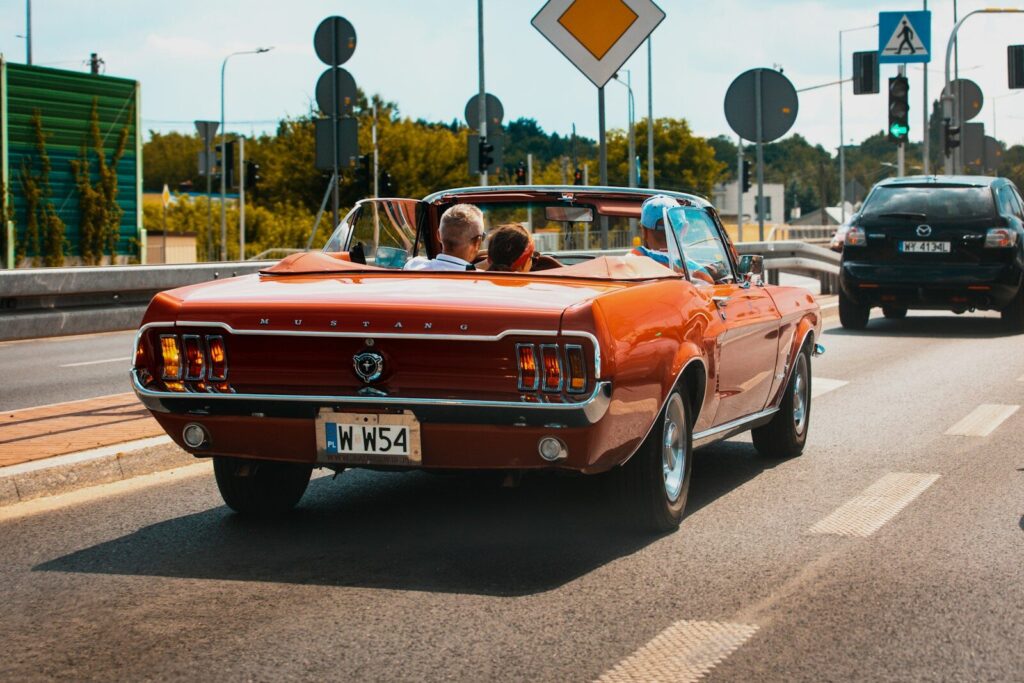 a red car driving down a street next to a traffic light