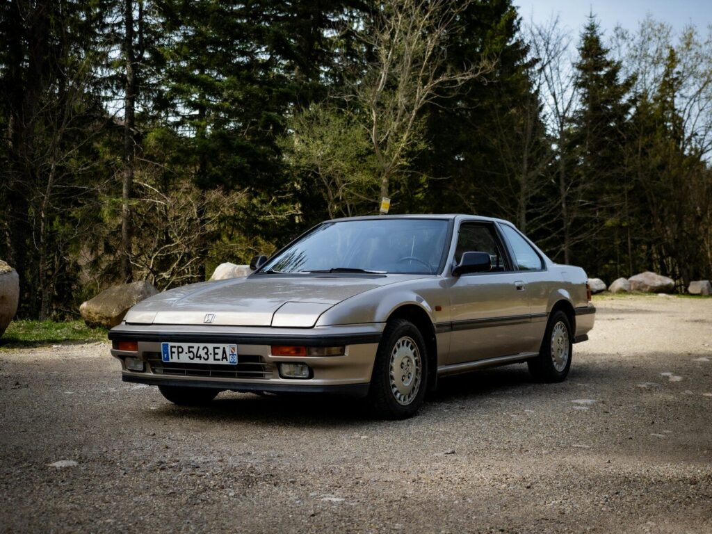 a silver car parked in front of some trees