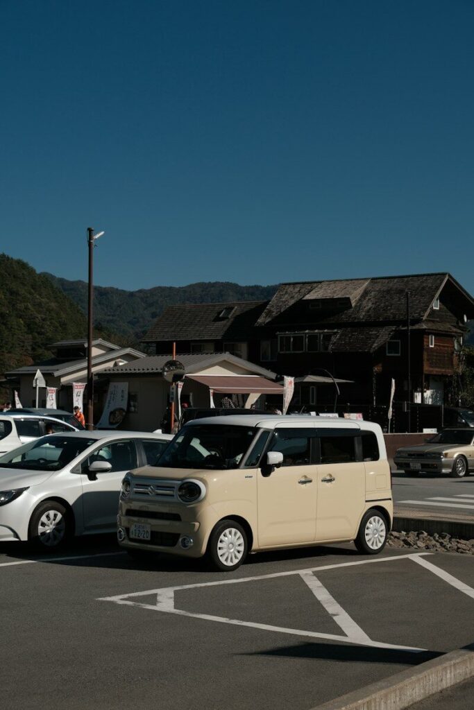 Several cars parked in a lot with buildings behind