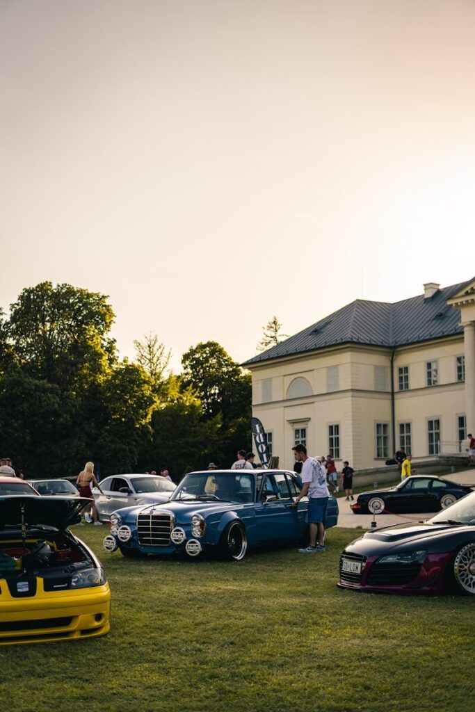 Classic cars displayed on a grassy lawn near a building