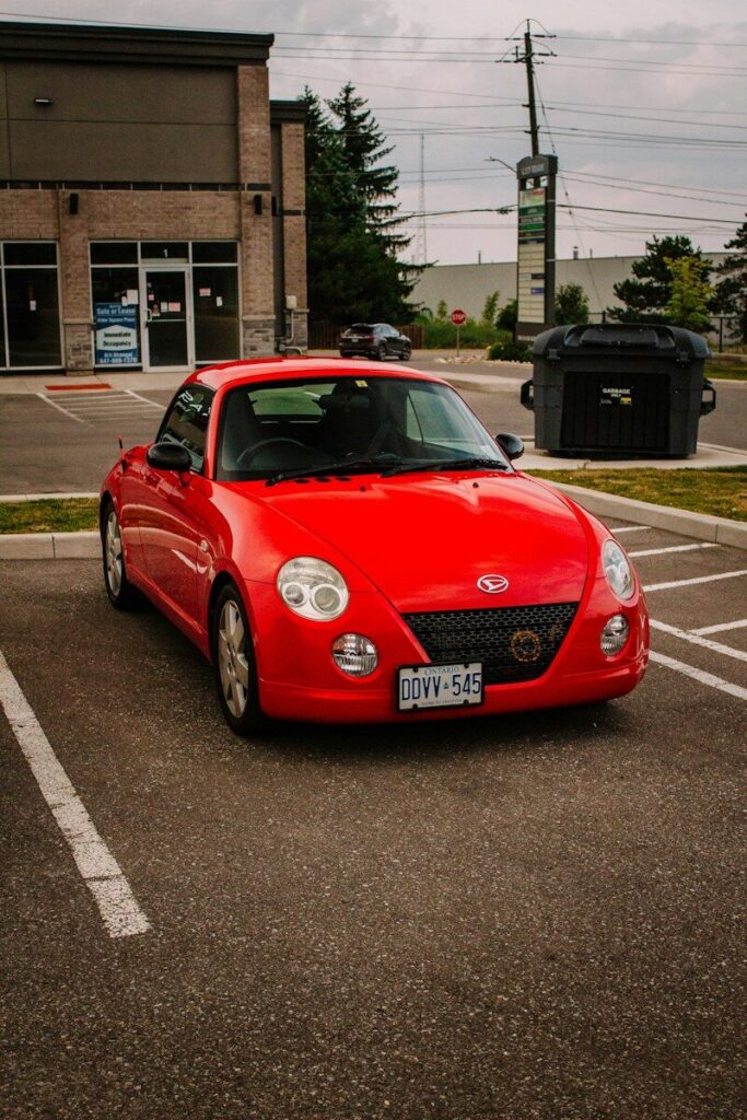 A red convertible car parked in a parking lot
