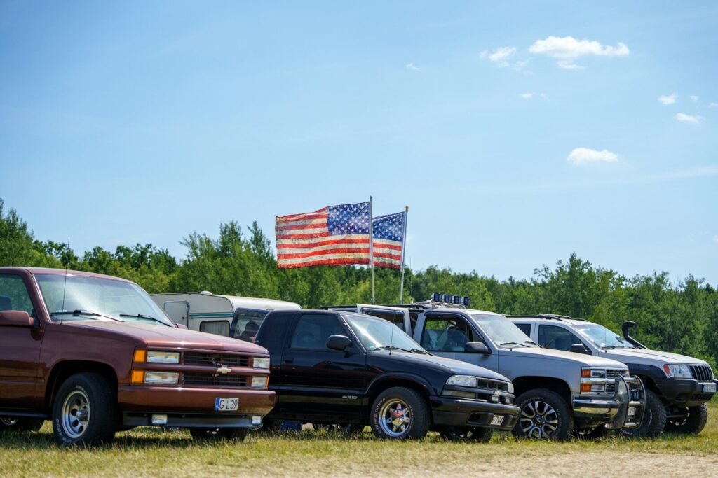 Pickup trucks and american flags under a blue sky