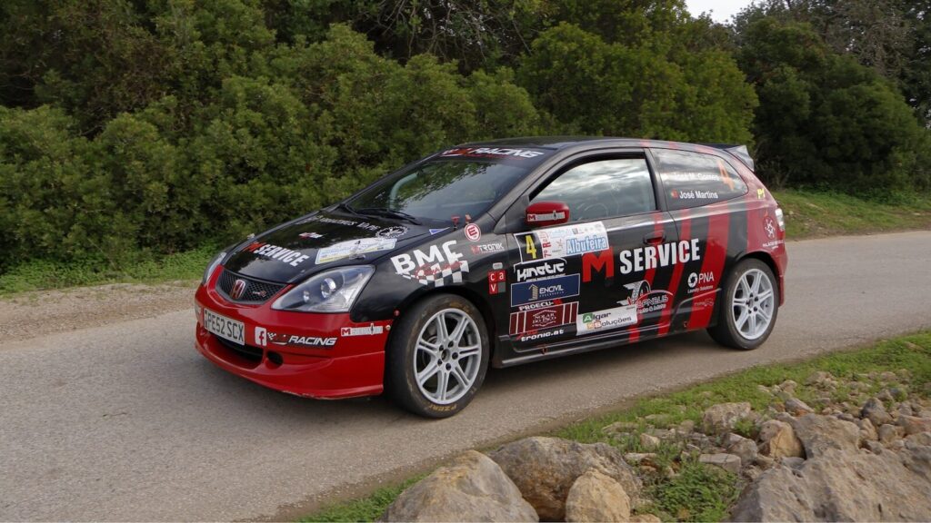 A red and black car driving down a road