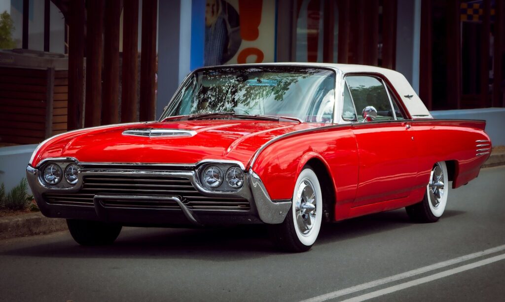 A classic red and white thunderbird car parked on street