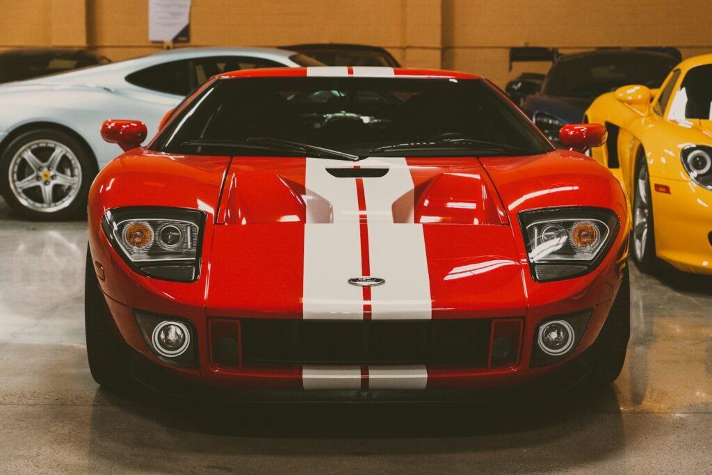 A red Ford GT with white racing stripes parked in a garage