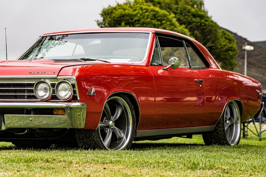 A classic red Chevrolet captured in vibrant detail, parked on a green field outdoors.