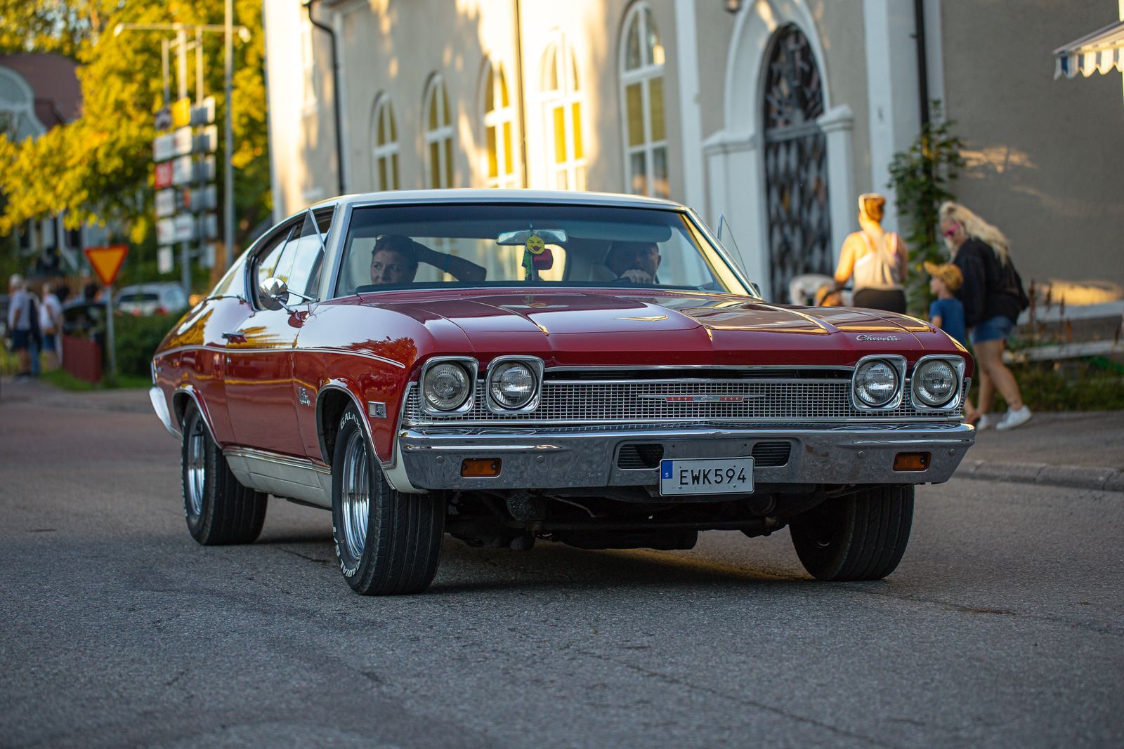Classic red Chevrolet Chevelle captured in an urban setting during daylight.