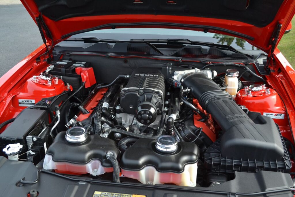 Close-up of a high-performance car engine with open hood, showcasing intricate parts.