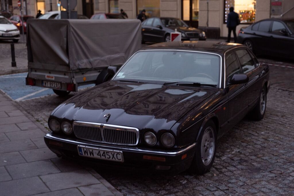 A vintage Jaguar car parked on a cobblestone city street, showcasing urban aesthetics.