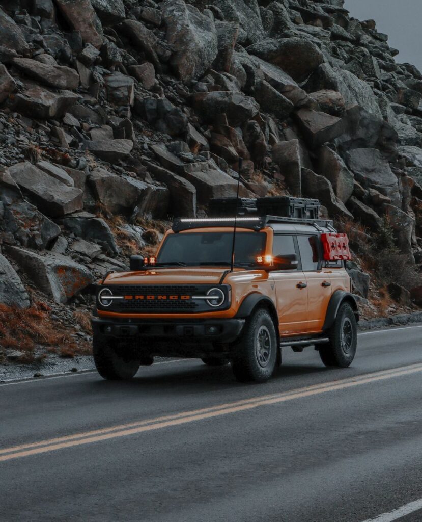 A Ford Bronco drives along a mountain road, showcasing adventure and exploration.