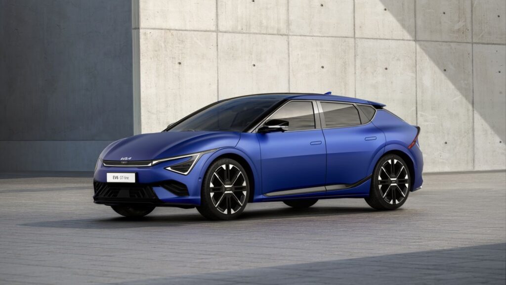 Modern blue electric car parked against a concrete urban wall.