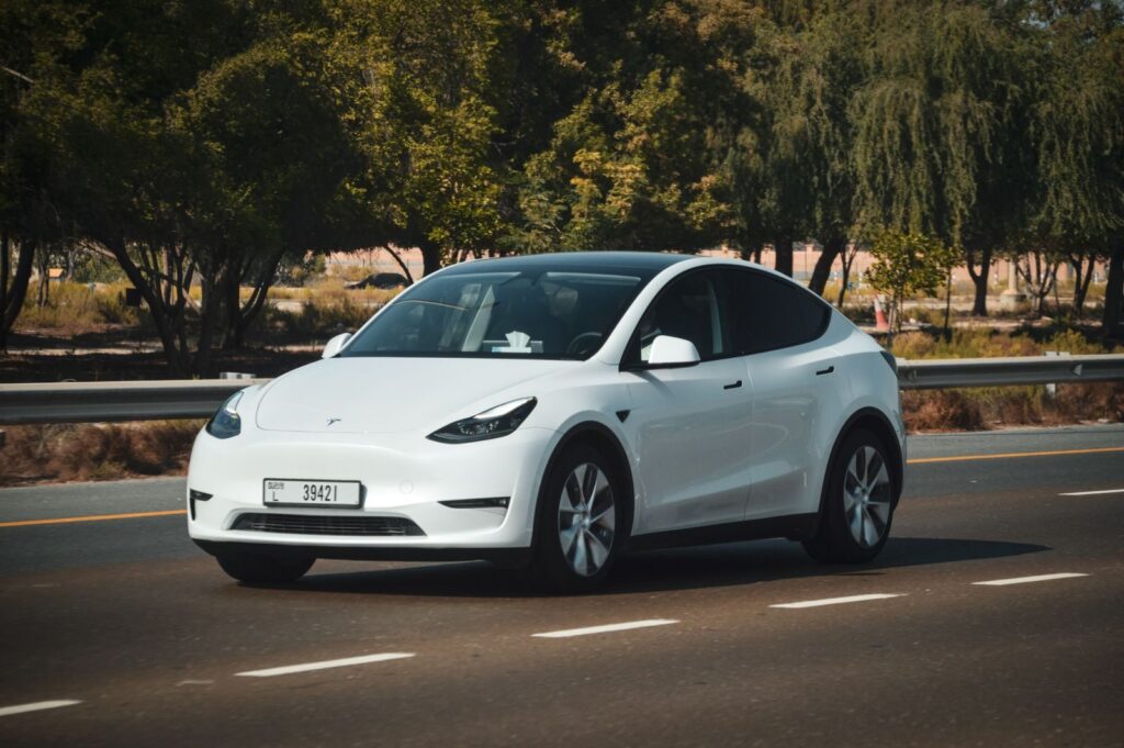 A sleek white electric car cruising on a sunny highway in Abu Dhabi, UAE.