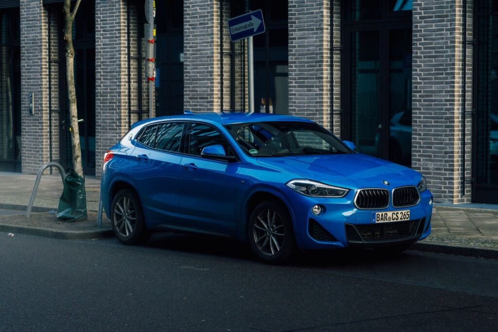 A vibrant blue SUV is parked against an urban brick wall, showcasing a sleek and modern design.